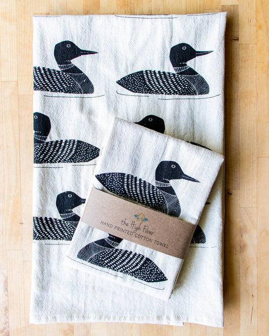 Set of tea towels with loon designs on a wooden surface