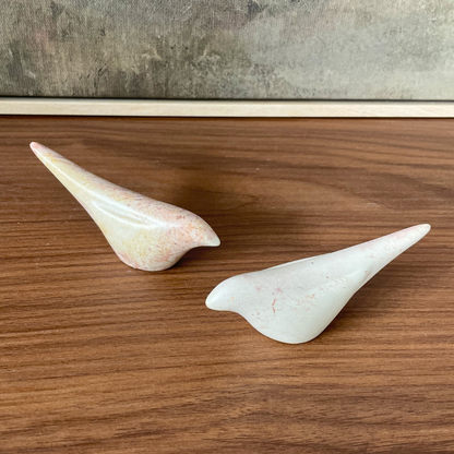 Two stone birds on a wooden surface with a neutral background