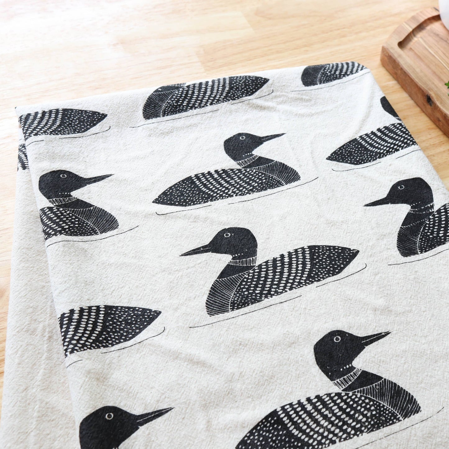 Fabric with black bird pattern on a wooden surface