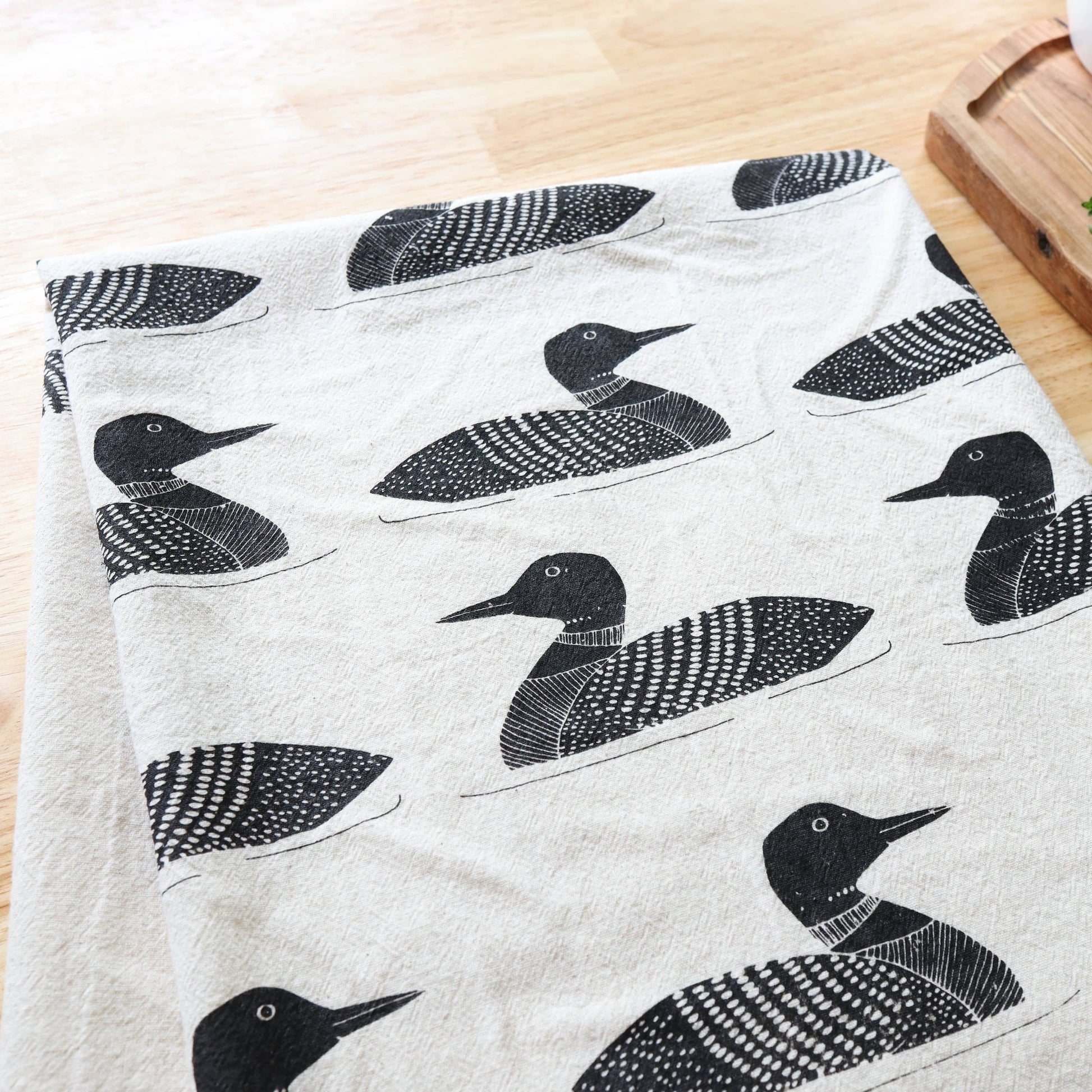 Fabric with black bird pattern on a wooden surface