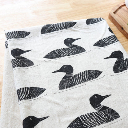 Fabric with black bird pattern on a wooden surface
