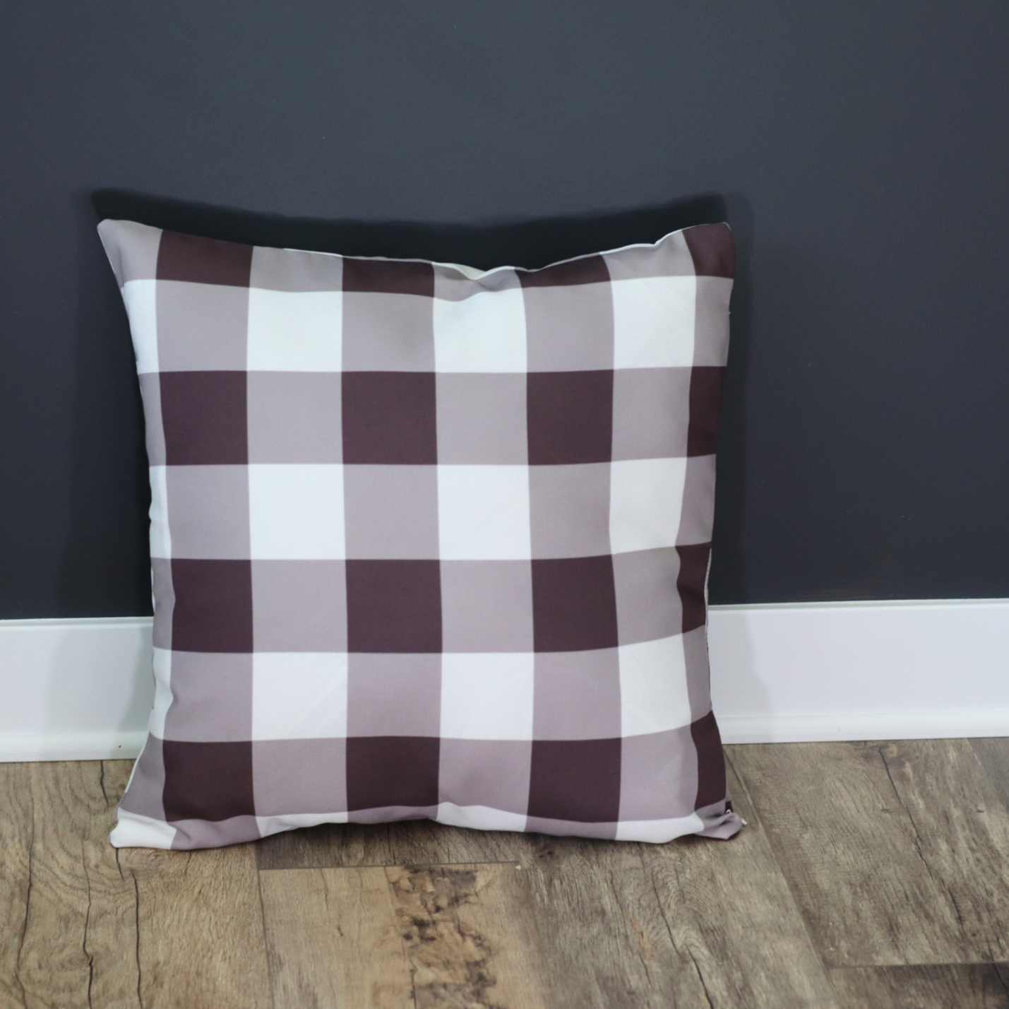 Checkered pillow on a wooden floor against a dark gray wall