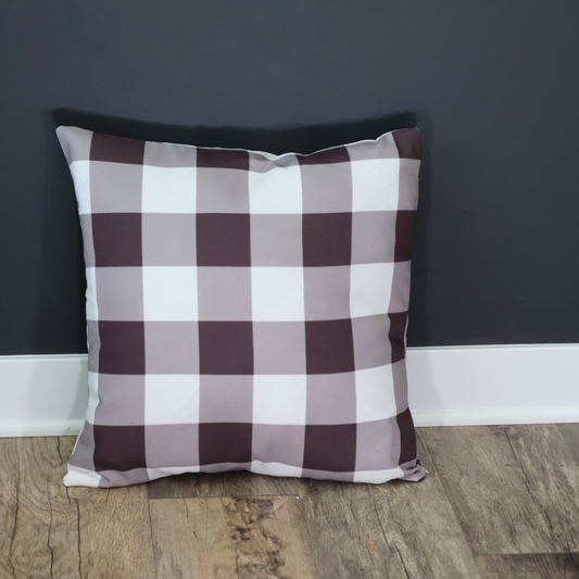 Checkered pillow on a wooden floor against a dark gray wall