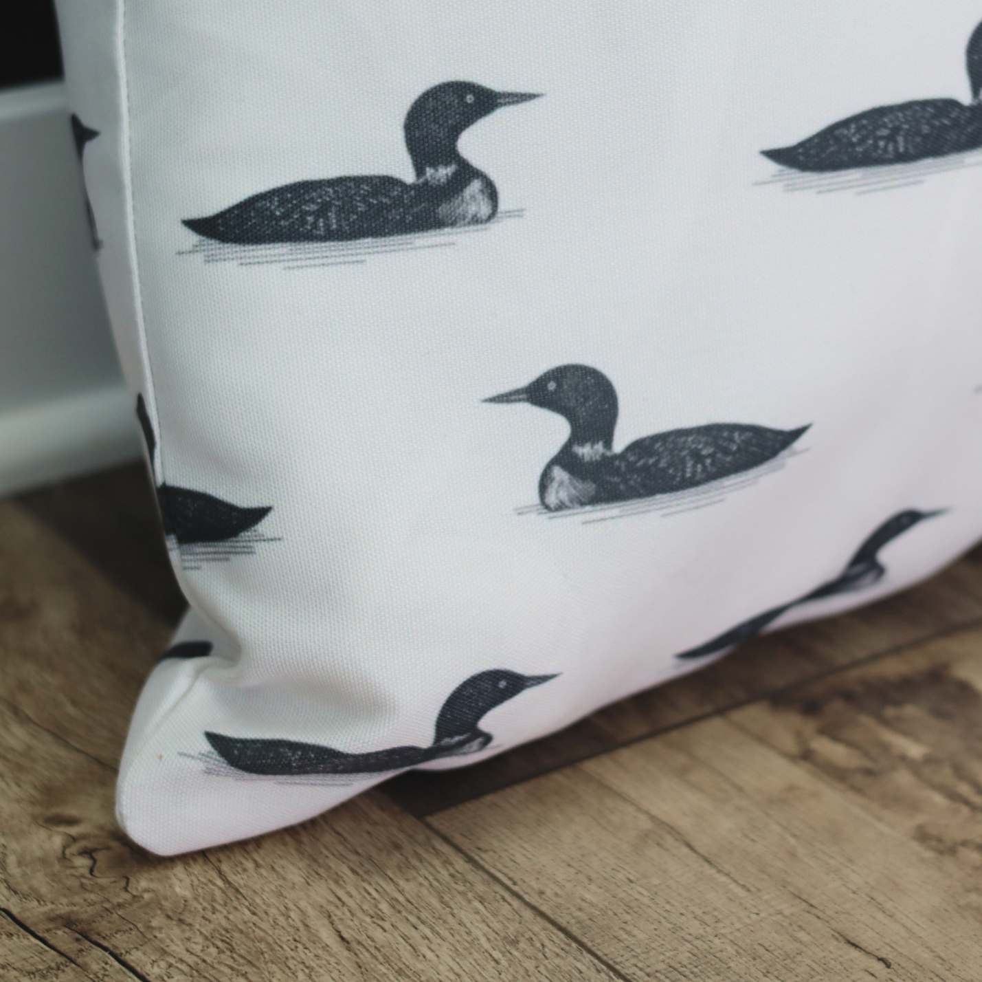 Pillow with black bird illustrations on a wooden floor