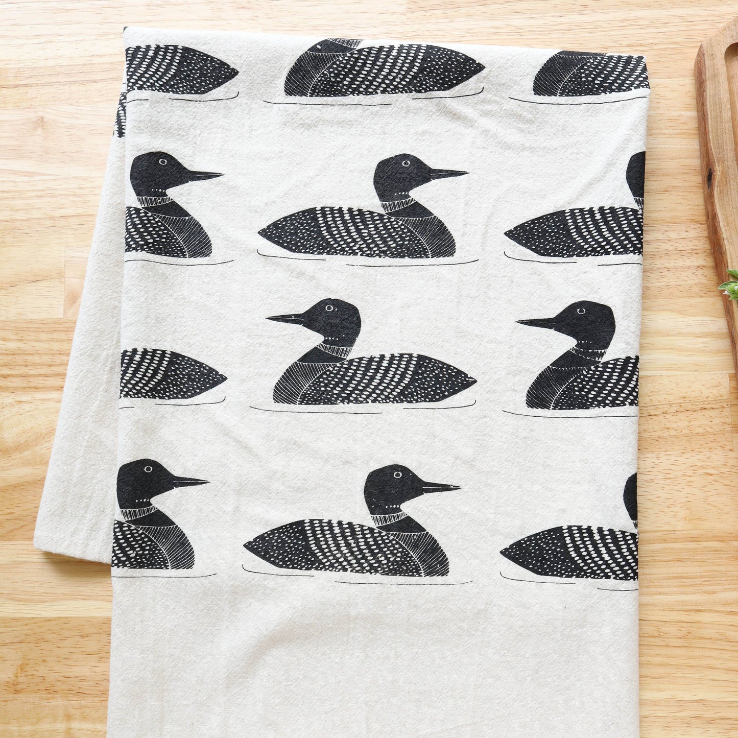 White towel with black duck pattern on a wooden surface