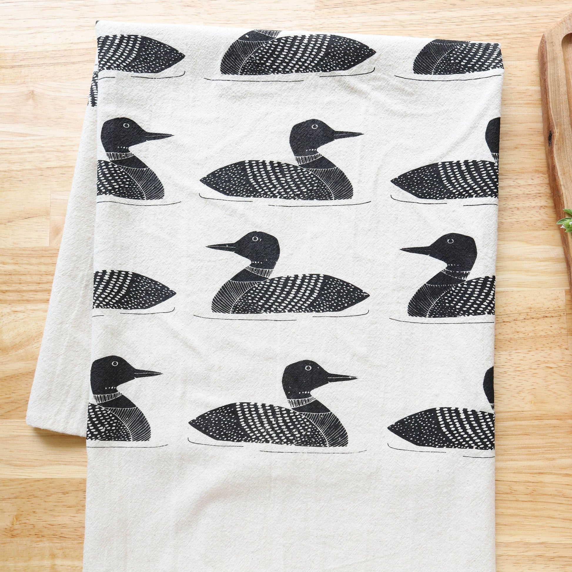 White towel with black duck pattern on a wooden surface