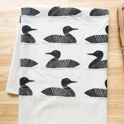 White towel with black duck pattern on a wooden surface