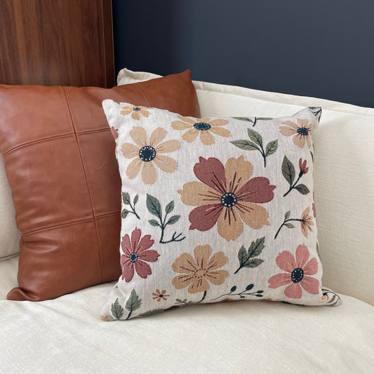 Floral-patterned pillow on a sofa with a brown leather pillow.