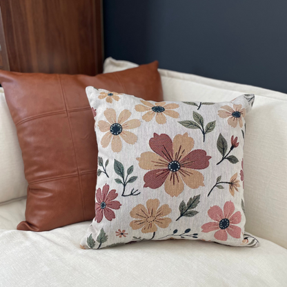 Floral-patterned pillow on a white couch with a brown leather pillow.