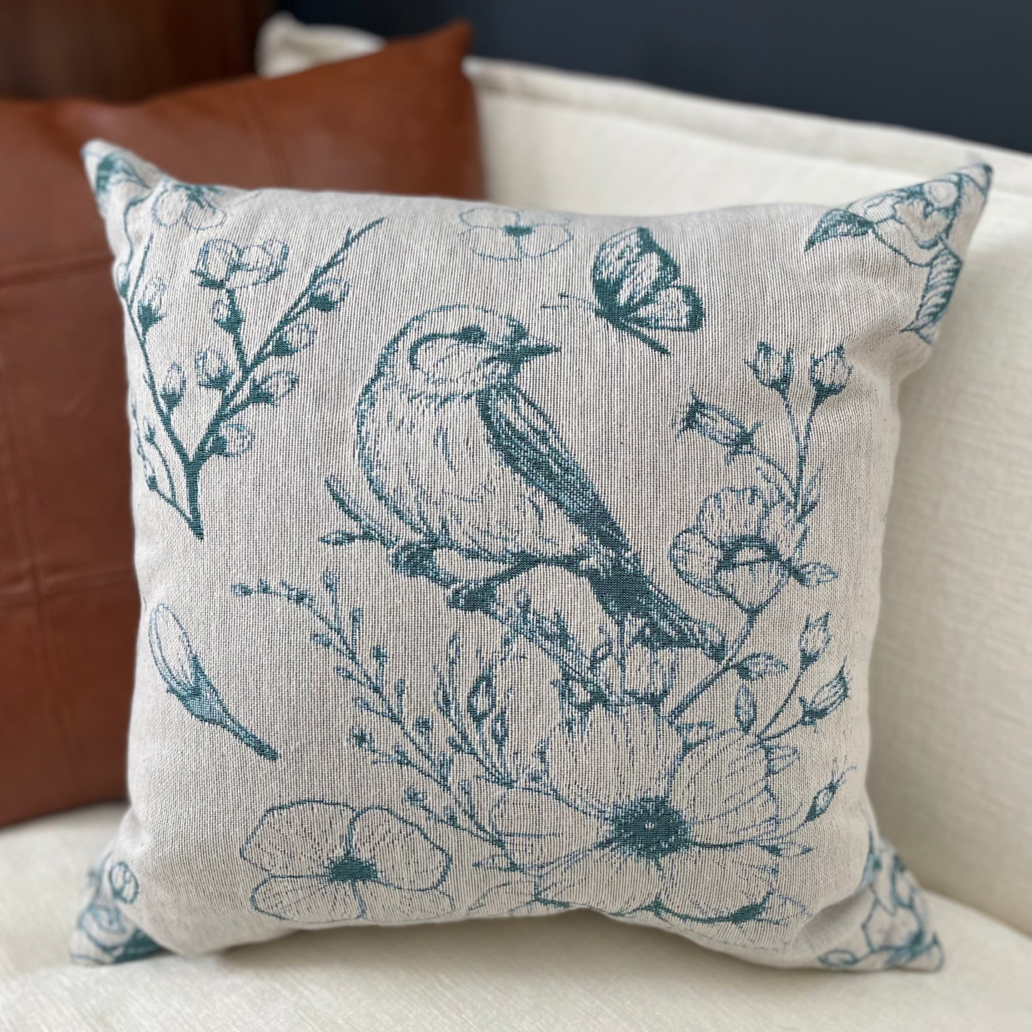 Decorative pillow with bird and floral pattern on a couch