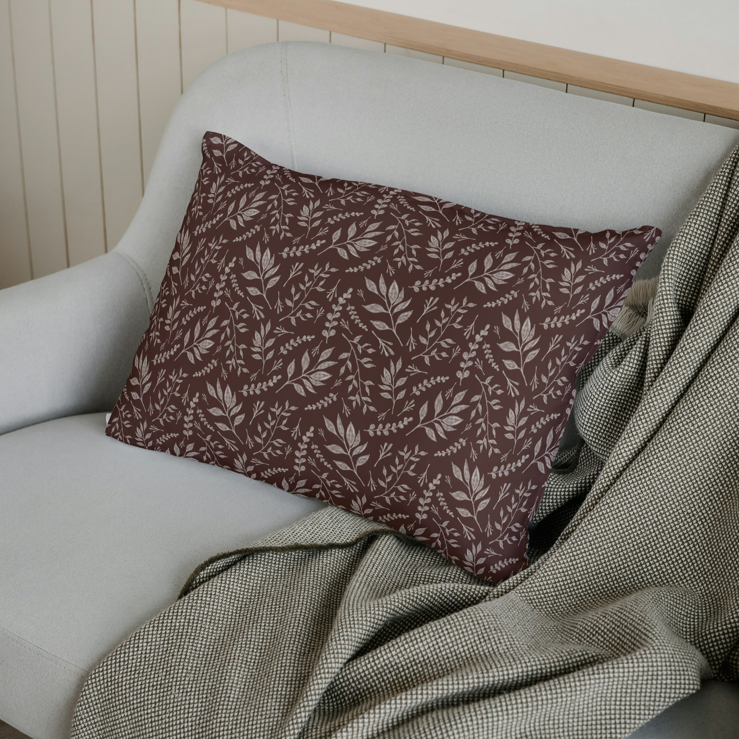 Decorative pillow with leaf pattern on a white sofa with a green blanket.