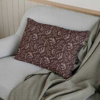 Decorative pillow with leaf pattern on a white sofa with a green blanket.