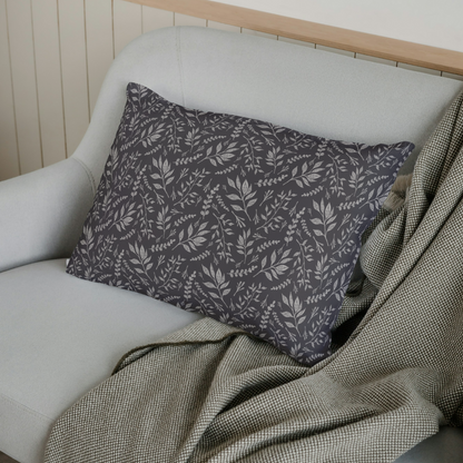 Gray pillow with leaf pattern on a white sofa with a green blanket