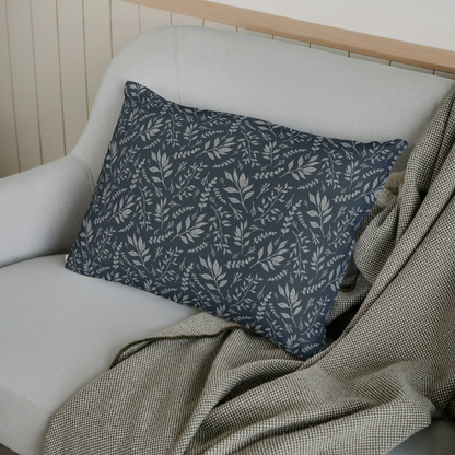 Gray cushion with leaf pattern on a white sofa with a wooden headboard.