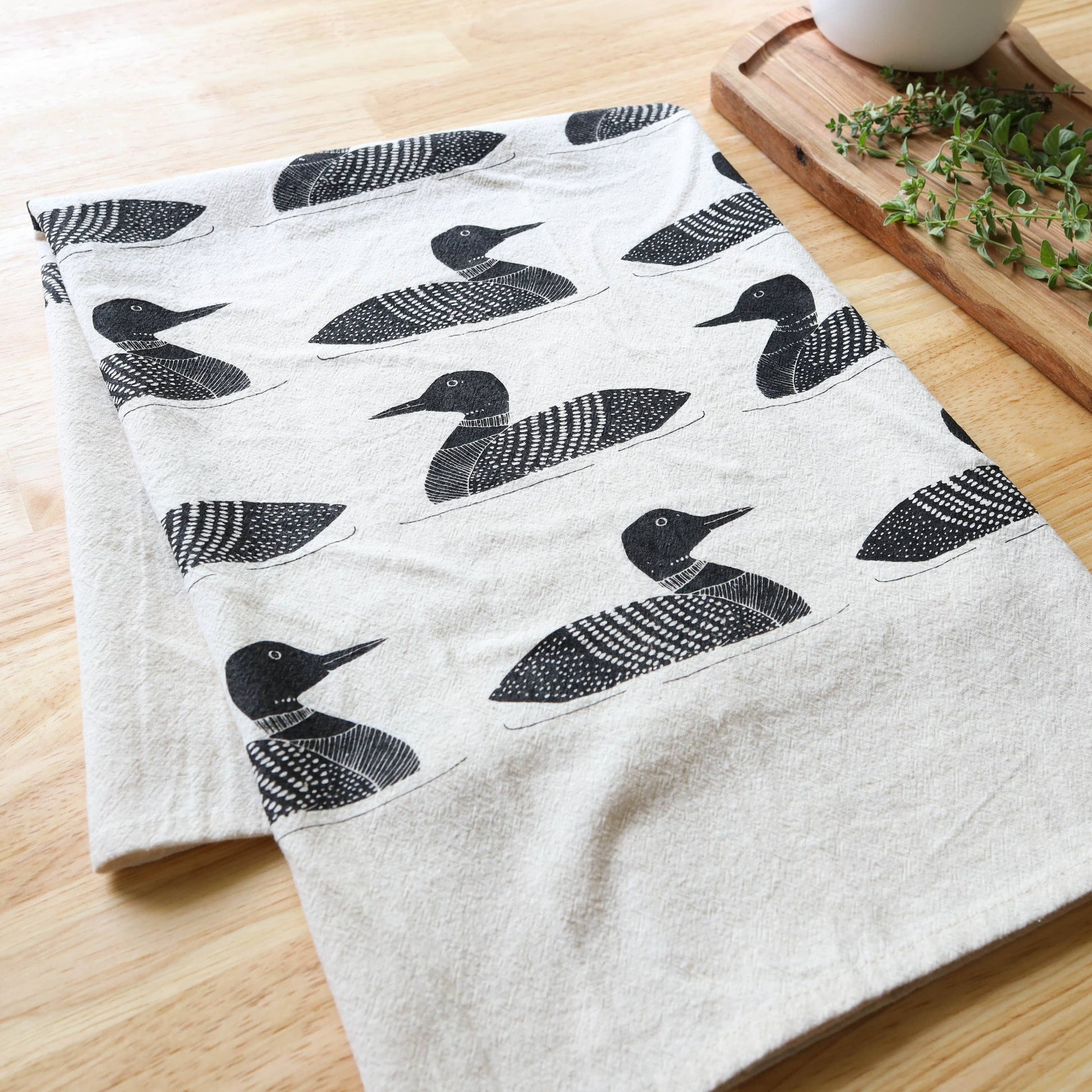 White towel with black duck pattern on a wooden surface