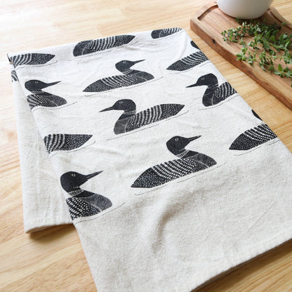 White towel with black duck pattern on a wooden surface