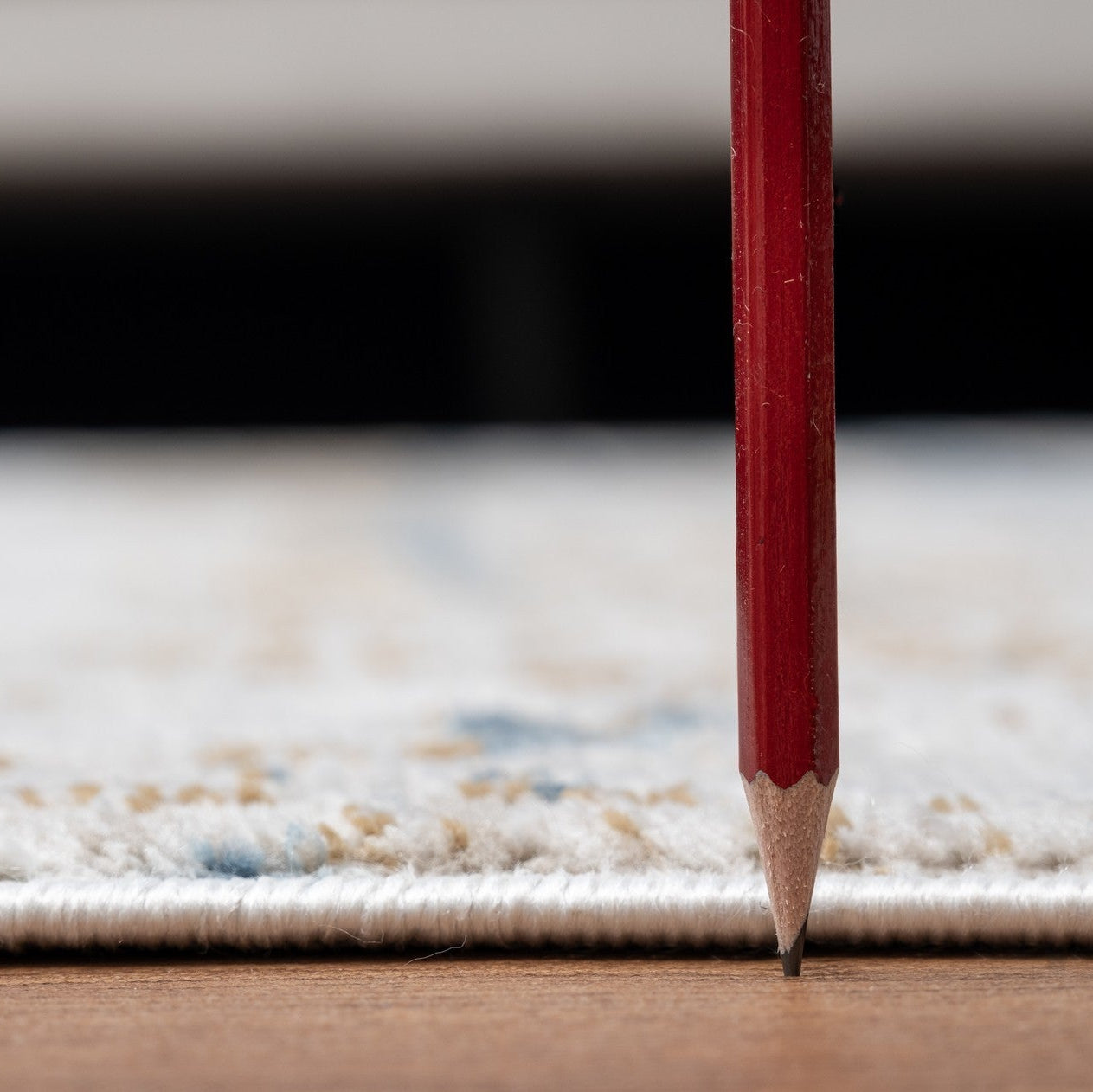 Red pencil standing upright on a textured surface with a blurred background