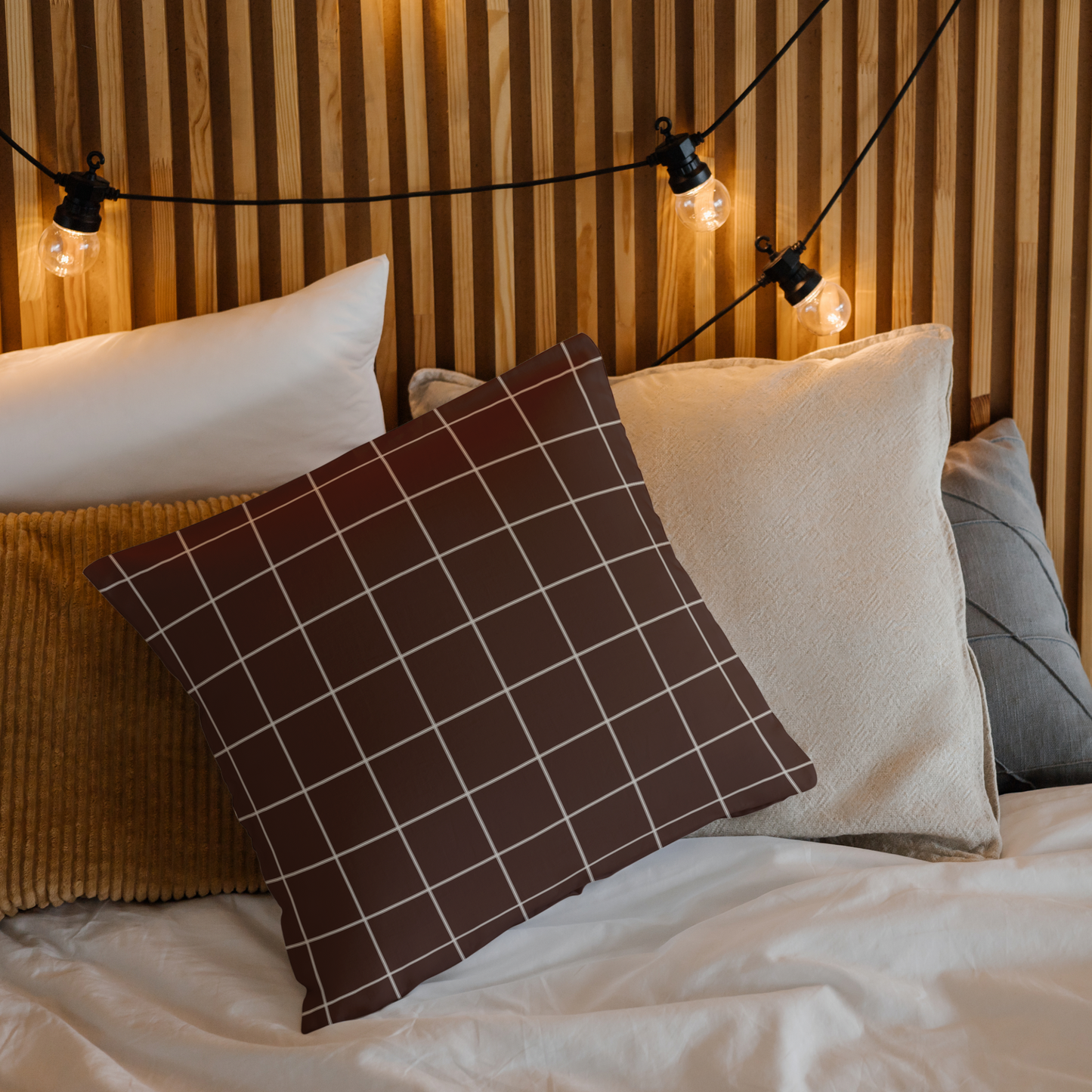 Decorative pillows on a bed with string lights in the background