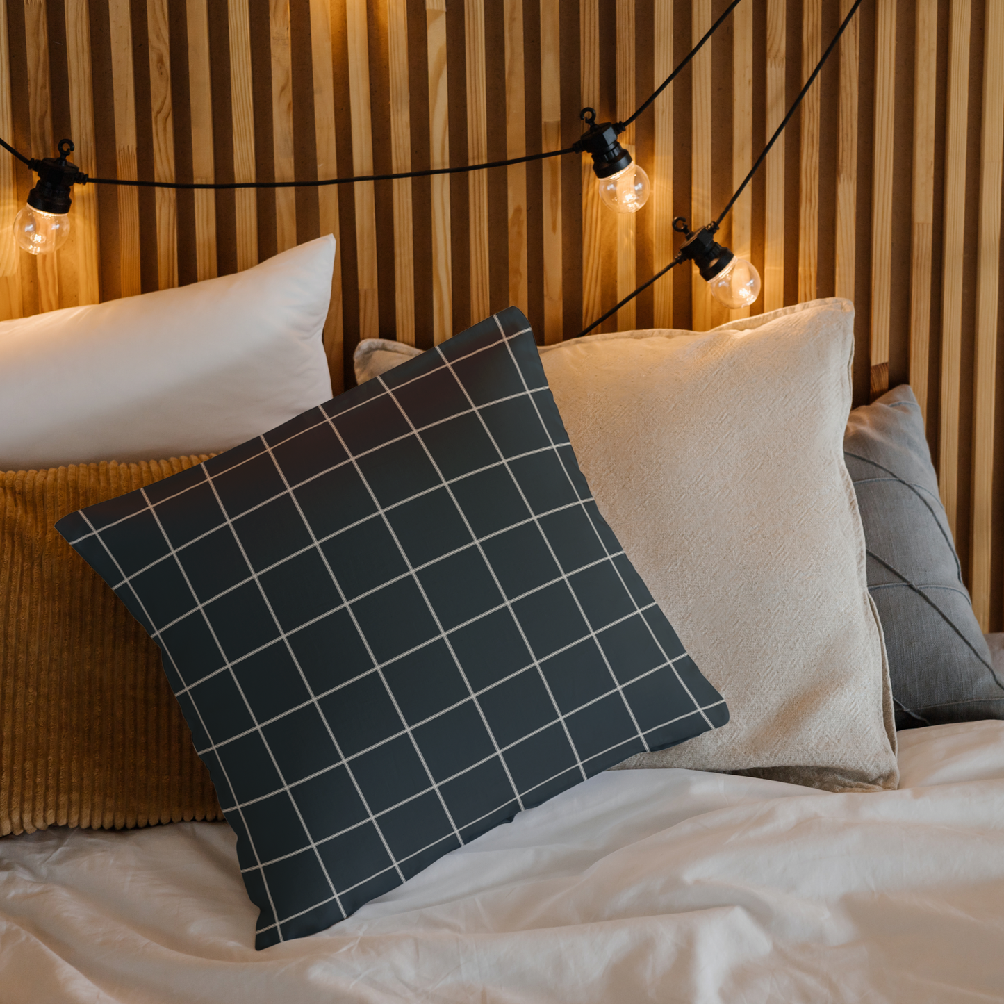 Decorative pillows on a bed with string lights in the background
