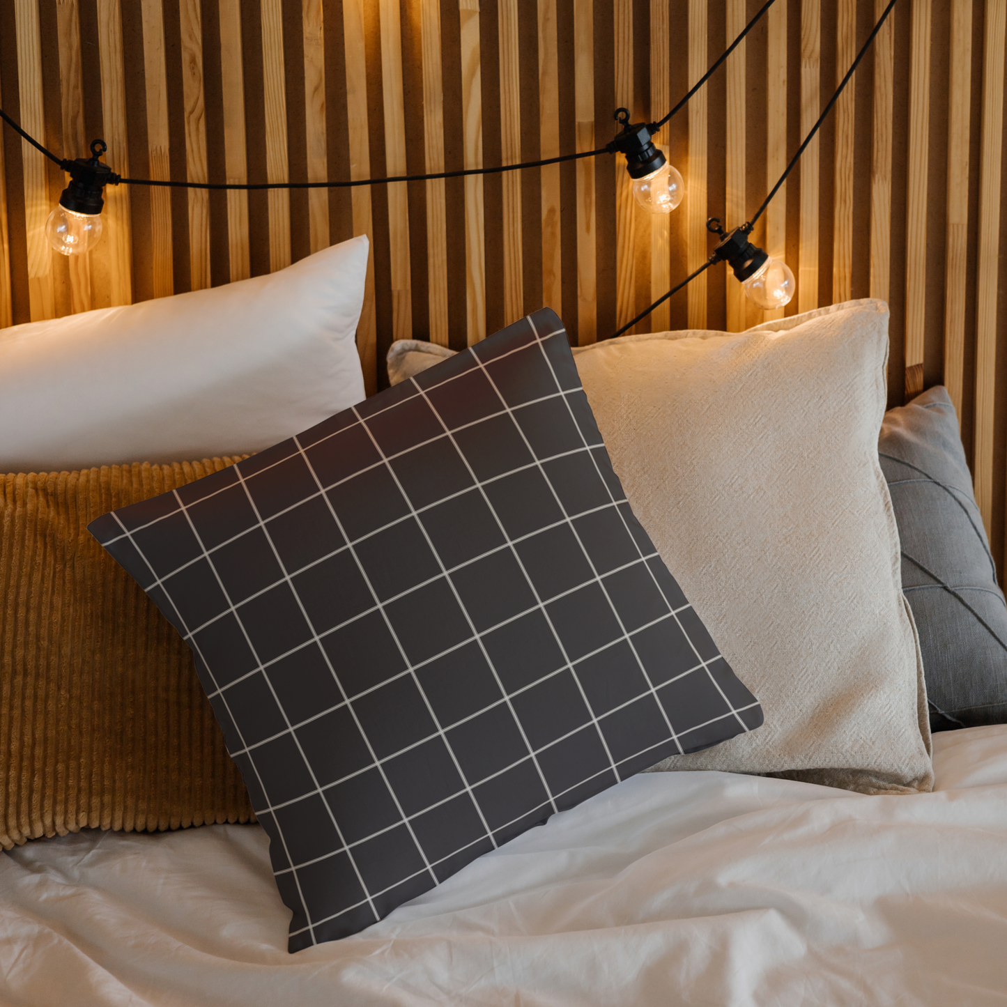 Decorative pillows on a bed with a wooden headboard and string lights.