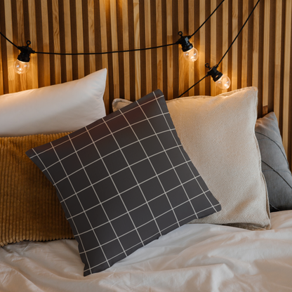 Decorative pillows on a bed with a wooden headboard and string lights.