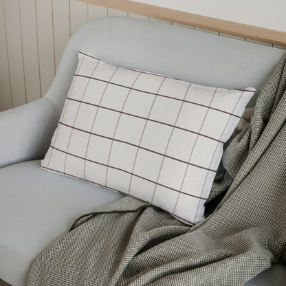 Gray sofa with a plaid pillow and green blanket against a white wall.